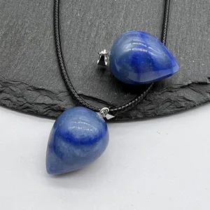 Close-up detail of blue drop-shaped crystal stone pendant with black cord necklace.