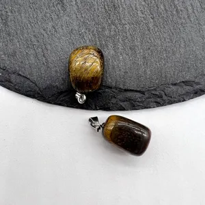 Close-up detail of natural tiger eye stone square pendant with metallic clasp on slate.