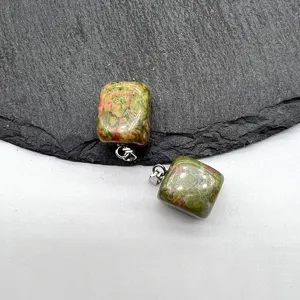 Close-up detail of natural gemstone square pendant with metal bail on slate background.