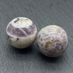 Detailed close-up of natural crystal stone sphere, polished purple mineral decor specimen.