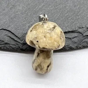 Detailed shot of a natural stone miniature mushroom pendant with a silver bail, gemstone charm.