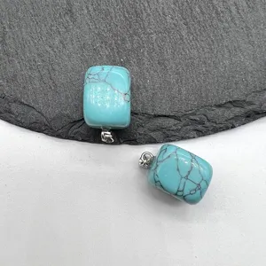 Close-up detail view of small square turquoise pendant stone with silver bail for necklace.