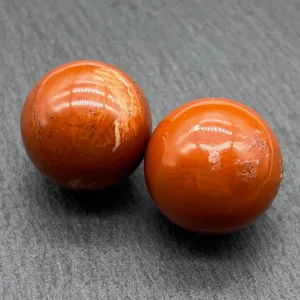 Detail shot of natural red crystal sphere gemstone mineral specimen polished smooth shiny surface.