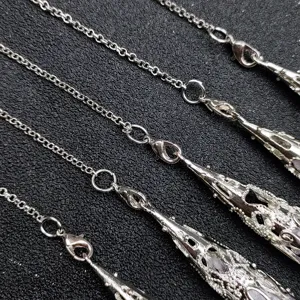 Raw crystal stone pendant detail showcasing intricate silver chain and hollow cone cage design.