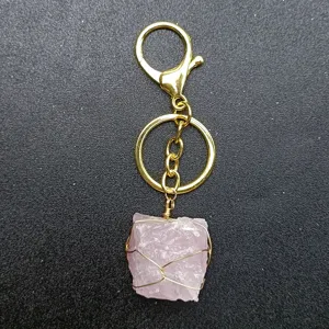 Portachiavi fatto a mano in cristallo di quarzo rosa grezzo con anello metallico dorato.