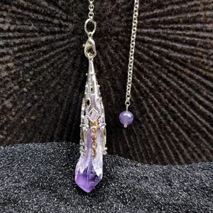 Close-up detail of natural amethyst crystal cluster pendant necklace with ornate silver cap.