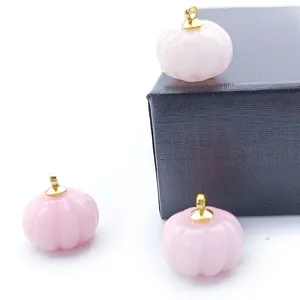 Close-up of pink carved crystal pumpkin pendant with gold bail for DIY handmade jewelry.