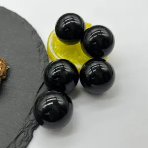 Natural black stone crystal ball detail view, polished smooth sphere for home decor display or healing energy.