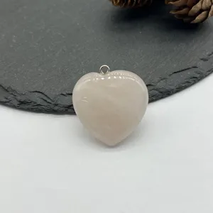 Close-up of a natural rose quartz heart pendant with silver bail for custom DIY necklaces.