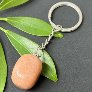 Close-up detail of natural crystal tumbled stone keychain with stainless steel ring and polished gem.