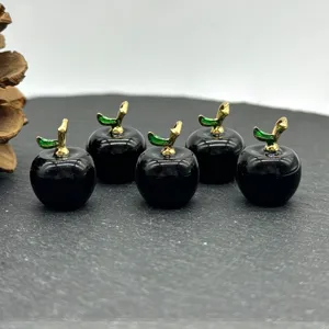 Close-up of small black gemstone apple pendant with gold stem and green leaf for DIY jewelry.