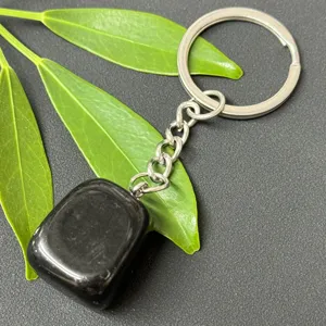 Natural black crystal tumbled stone keychain detail showing smooth polished surface and steel ring.
