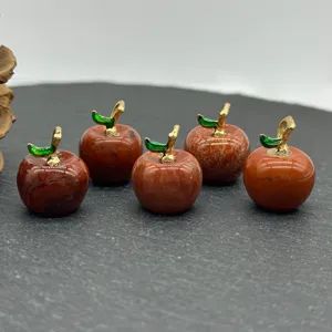 Close-up of five small red gemstone apple pendants with gold stems, detail view.