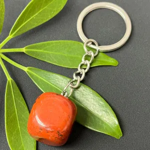 Red tumbled stone pendant keychain detail view, polished gemstone charm close up shot