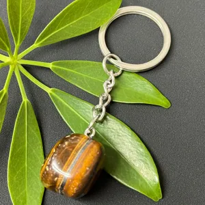 Detailed view of natural tiger eye stone tumbled gemstone pendant with stainless steel keychain.