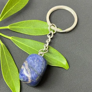 Detail shot of polished blue crystal gemstone keychain with stainless steel ring and green leaf decor.