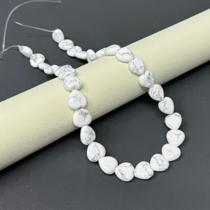 Close-up of white heart-shaped gemstone beads strand, perfect for DIY jewelry making.