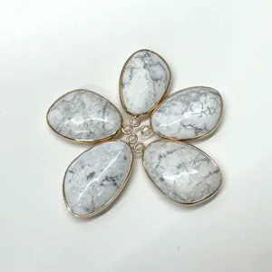 Gedetailleerd uitzicht op druppelvormige witte steenhangers met gouden rand voor sieraden.