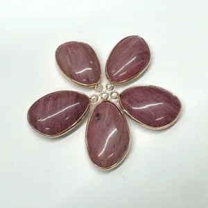Gedetailleerd overzicht van roze edelsteenhangers met gouden rand voor DIY sieraden maken.