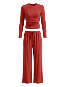 Close-up detail of brick red long sleeve gathered top and wide leg lounge trousers.