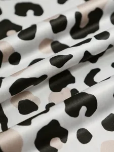 Gros plan de tissu satin de soie avec texture lisse et design imprimé animal abstrait pour vêtements.