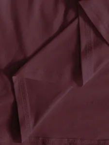 Gros plan détaillé sur le tissu de la robe bordeaux avec une texture lisse et coutures nettes.