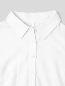 Gros plan sur le col et la patte de boutonnage blanche de la combishort chemise.