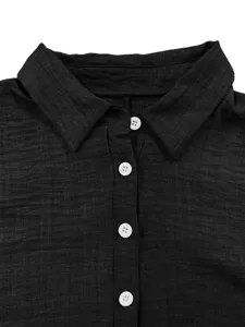 Gros plan détail d'un col de chemise noir avec des boutons blancs et un tissu texturé.