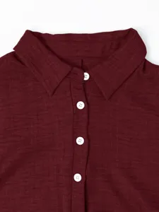 Gros plan detaille d un chemisier rouge fonce avec col et boutons blancs, belle texture.