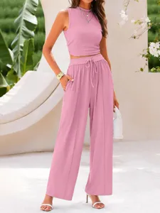 Detail view of the pink ribbed crop top and wide-leg trousers set in an elegant resort scene.