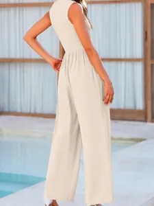 Back detail view of women's sleeveless beige wide-leg jumpsuit, elegant poolside setting.