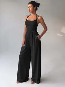 Detail view of casual black wide-leg jumpsuit, featuring thin straps and loose fit.