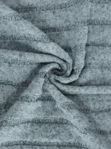 Gros plan détaillé d'un tissu en maille rayé gris doux, montrant la texture et la matière.