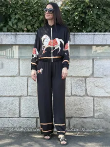 Detail shot of the black two-piece tracksuit featuring vintage horse prints and contrasting trim.