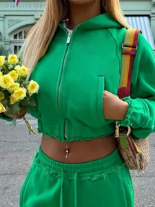 Detail shot of green cropped zip-up hoodie and sweatpants set featuring raw edges and pockets.