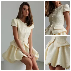Tweed dress detail view showing ivory white fabric texture, round neck and short sleeves.