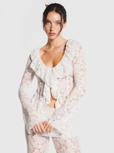 Detailed view of white lace ruffle v-neck long sleeve crop top and matching trousers set.