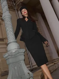 French chic black suit detail, stand collar peplum jacket and midi skirt in architectural scene.