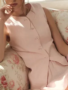 Pink sleeveless button-down vest and skirt detail, stylish summer two-piece outfit.