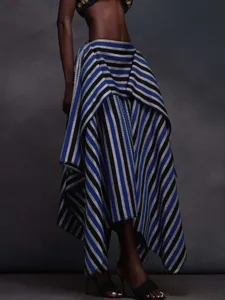 Detail shot of a stylish striped asymmetric tiered long skirt with metallic sheen and drape.