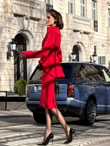 Exquisite details of the red peplum suit jacket and midi skirt set in street style view.