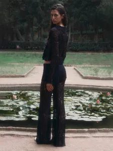 Detailed view of the black lace crop top and wide-leg pants set in an outdoor garden.
