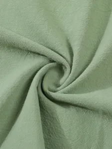 Vue détaillée du tissu en lin vert clair, montrant une texture douce et des plis naturels.