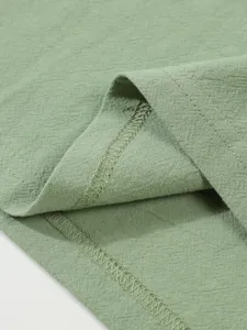 Gros plan sur la texture du tissu de chemise en lin vert clair et les détails de surjet.