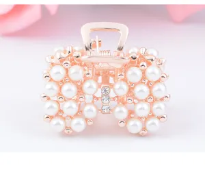 Détail en gros plan de la pince à cheveux métal perles et strass en or rose.