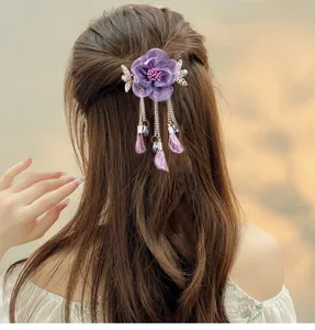 Detailed view of purple fabric flower hair clip with elegant metal tassels for vintage hairstyles.