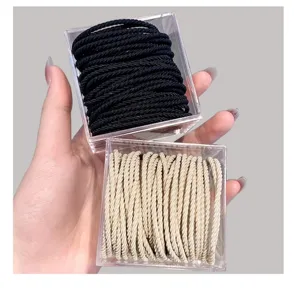 Detail view of boxed elastic hair ties in black and beige, neatly stored in clear cases.