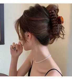 Detailed view of a stylish brown tortoiseshell hair claw clip for women. Elegant hair accessory.