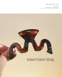 Detailed view of the brown frosted wavy hair claw clip, showing its unique shape and size.