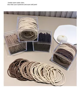 Close-up detail of minimalist braided hair ties in transparent storage boxes with neutral colors.
